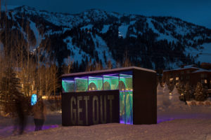 Art installation lit up at night below the mountains.