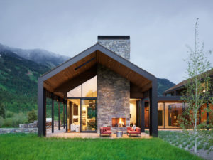 Modern mountainside home with outdoor fireplace and seating area.