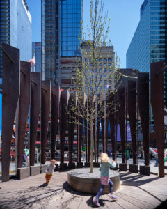 Two children play next to an outdoor art display in a city.